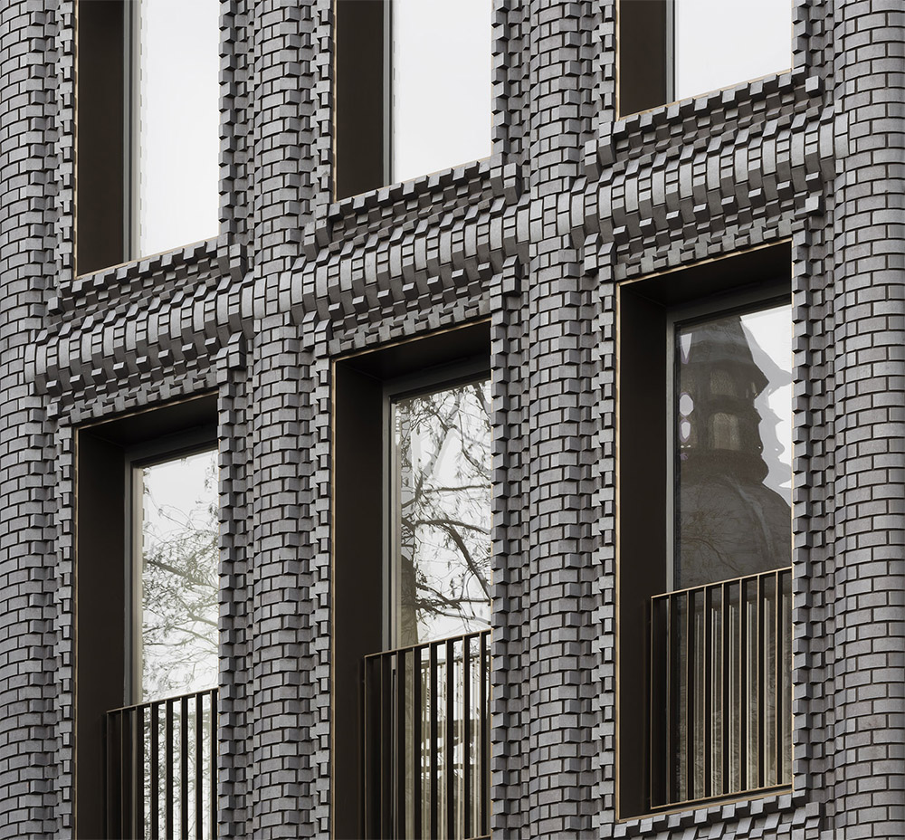Close-up photo of a facade of interlocking blue-gray bricks that appear to be rotating in and out of each other