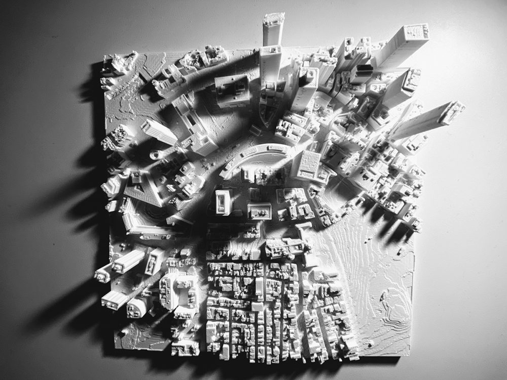 A top-down view of a white plastic tile with a 3D map of a city.