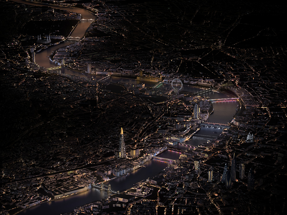 A bird's eye view of London with bridges across the Thames lit up colorfully