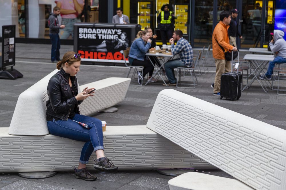 A person sits on interlocking benches in Times Square.